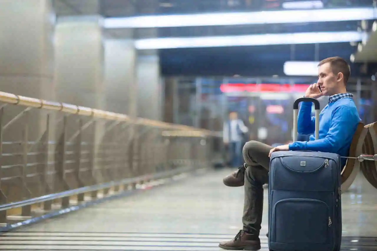 homem no celular aguardando no saguao do aeroporto